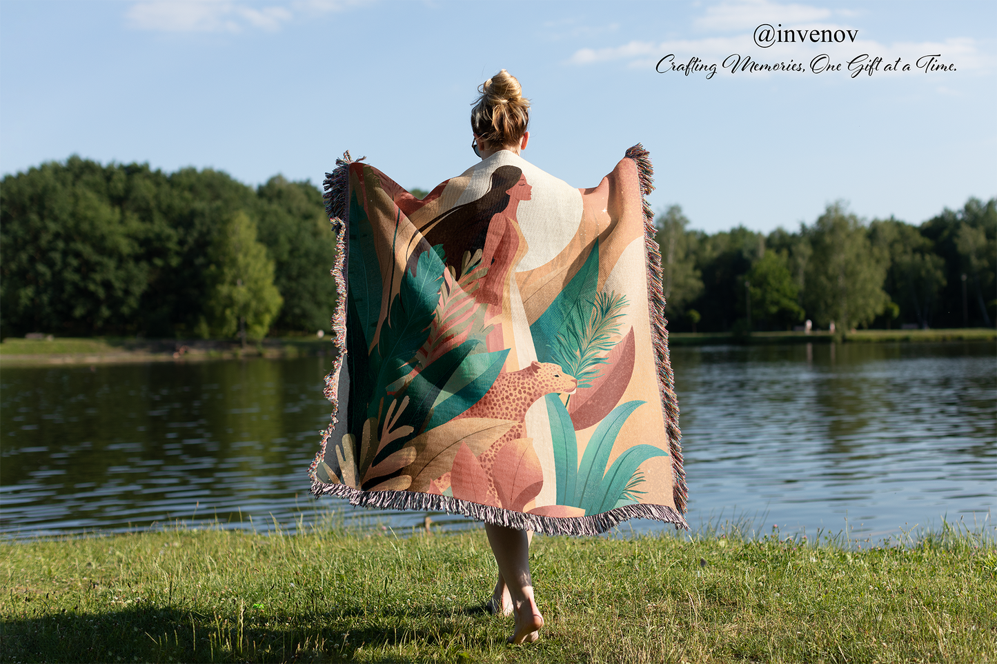 Person walking by a lake with a colorful towel draped over their shoulders, featuring nature-themed designs.