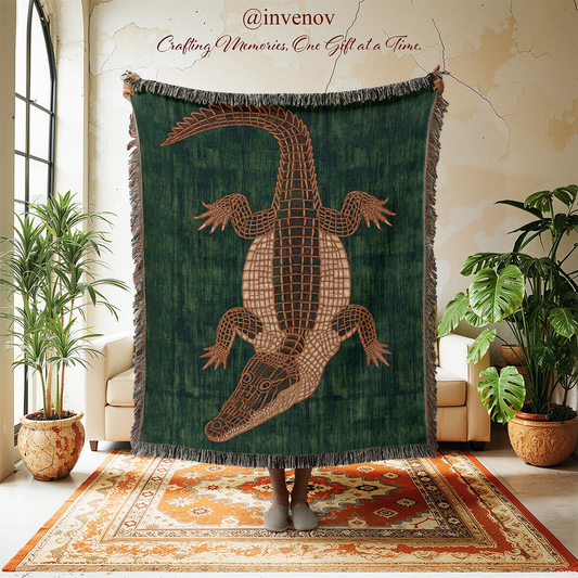 A large woven throw blanket with a dark green background and a large brown alligator design in the center, held up by a person standing on a patterned rug in a styled room with plants and a chair.