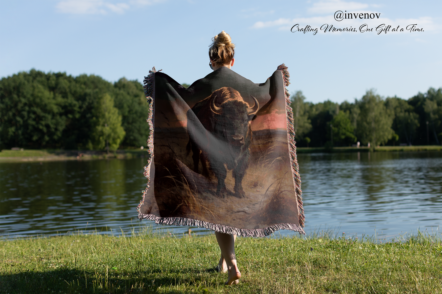 Person holding a blanket with a bear design by a lake