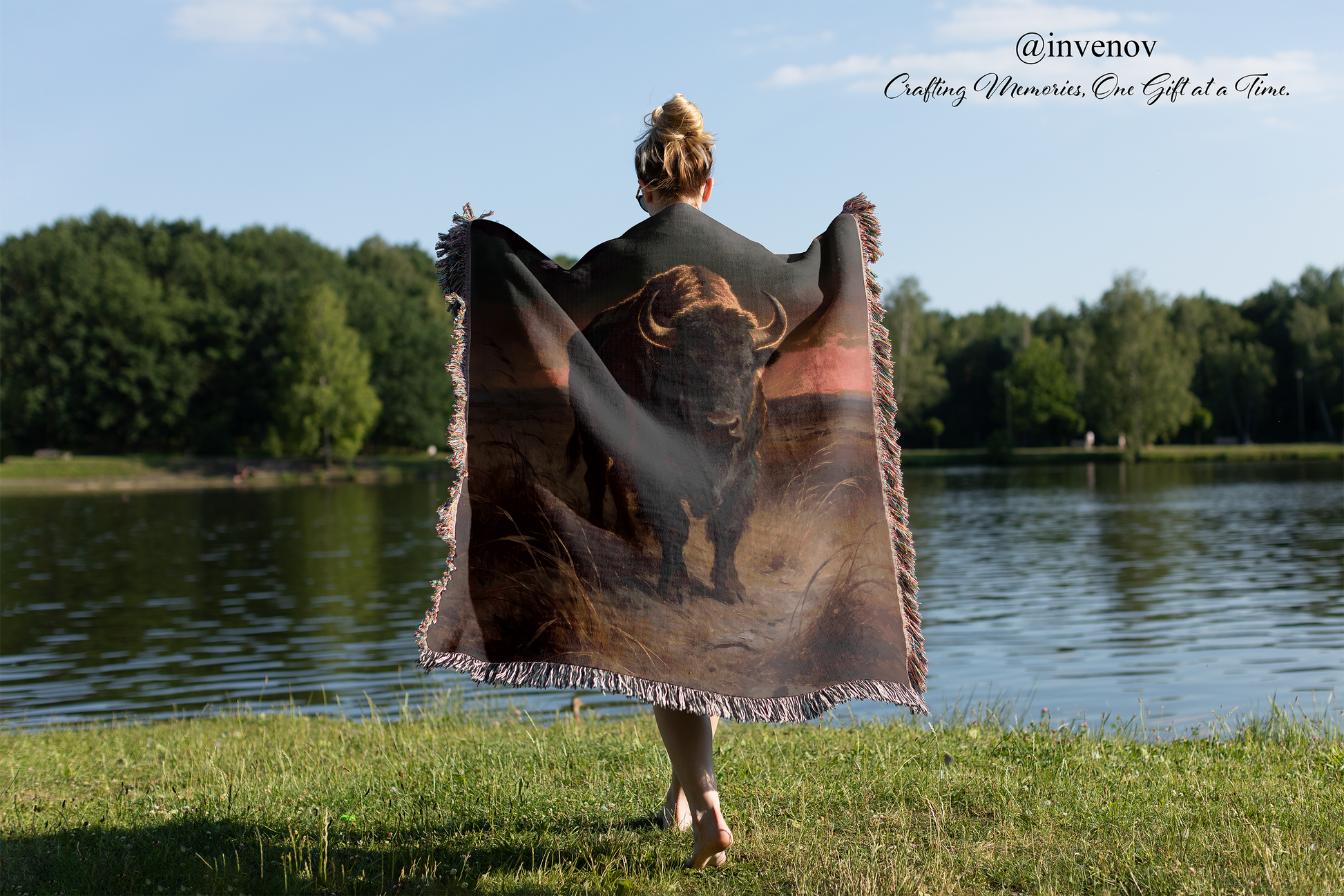 Person holding a blanket with a bear design by a lake