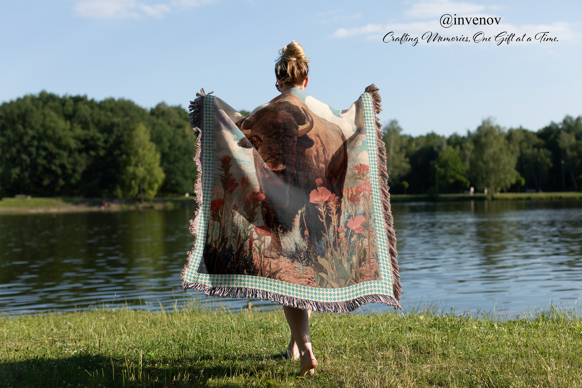 Person holding a blanket with a bison design by a lake