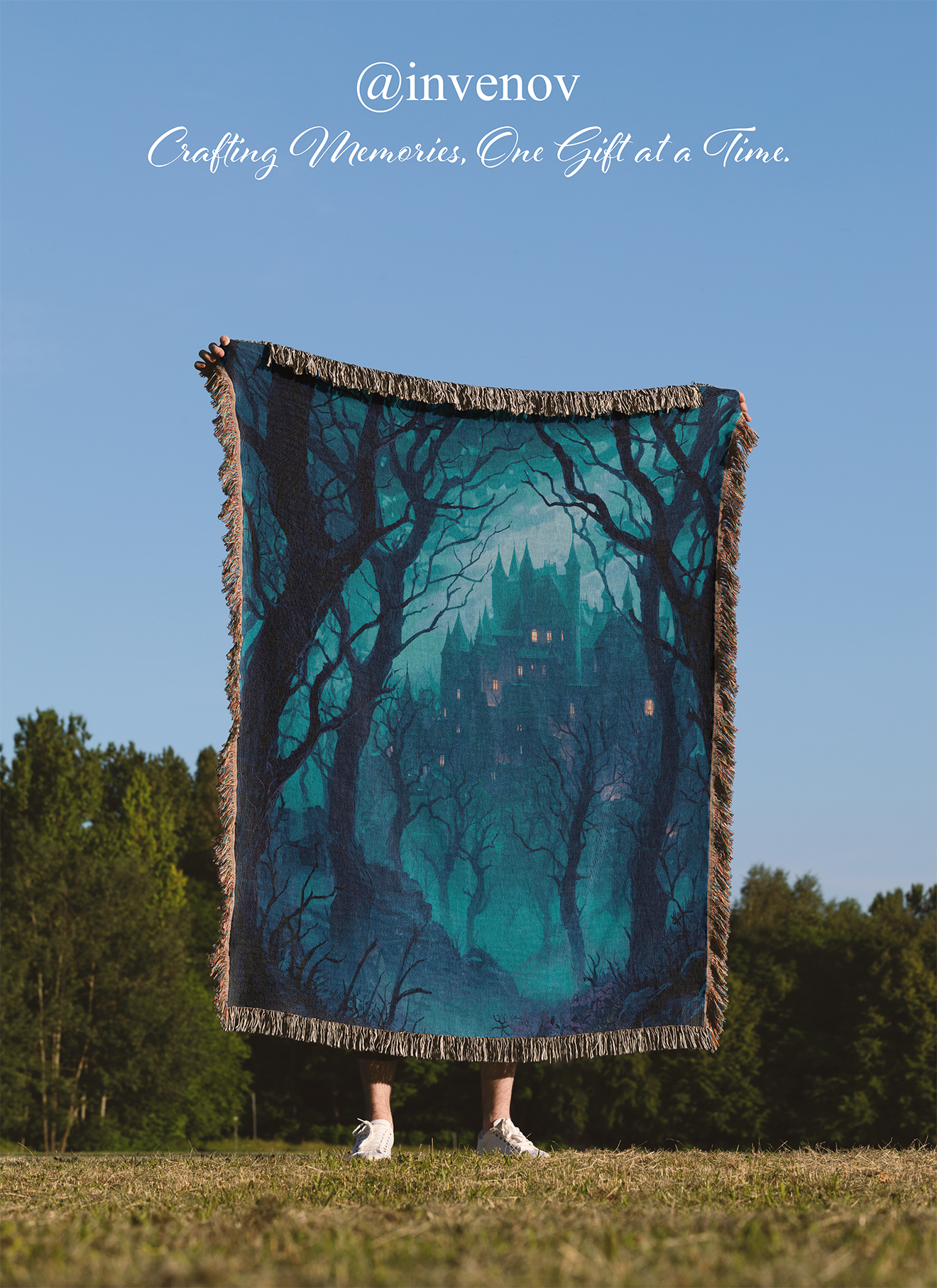 Person holding a large blanket with a forest design against a clear blue sky.