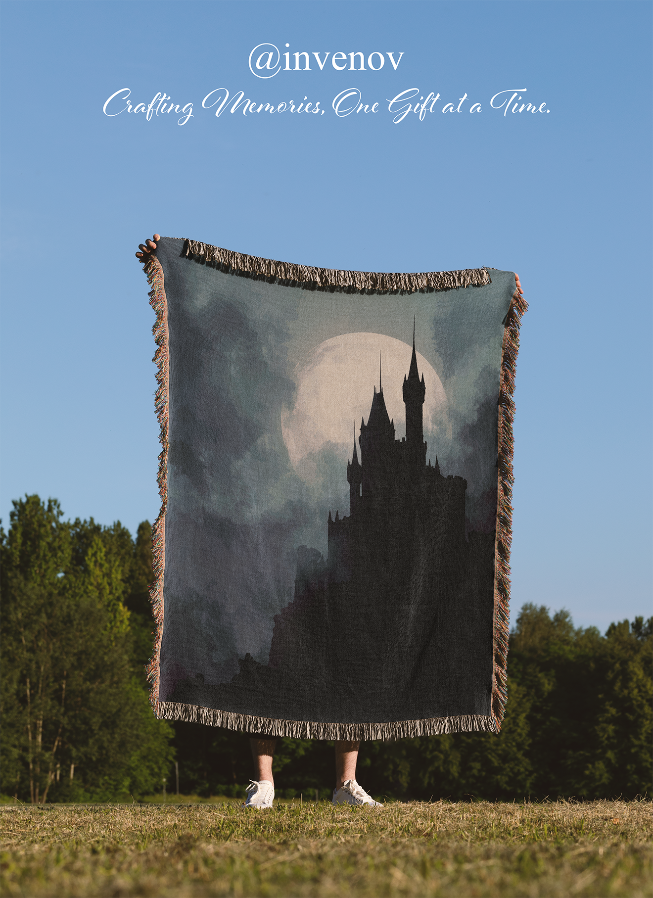 Person holding a blanket with a castle design against a blue sky.