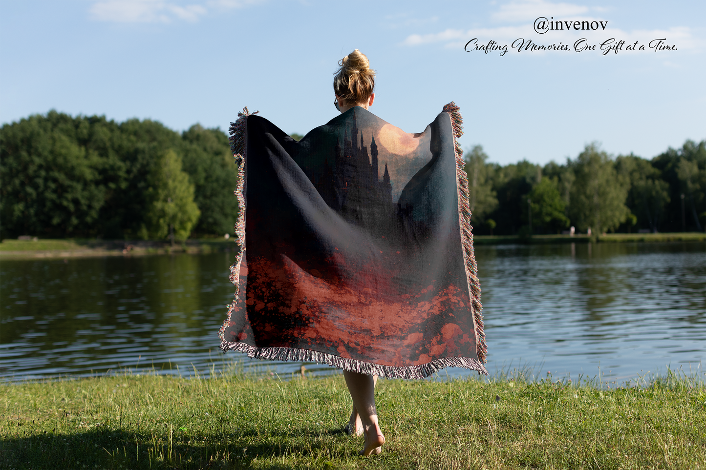 Person holding a large, patterned fabric by a lake with trees in the background