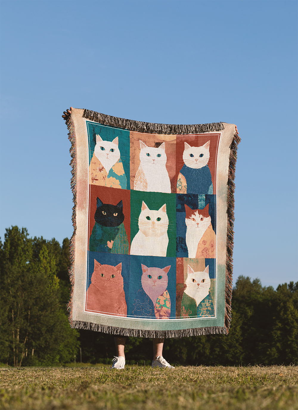 Person holding a blanket with cat pattern against a blue sky and trees background