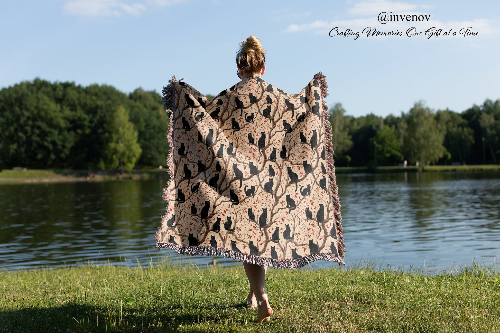 Person holding a patterned blanket by a lake with trees in the background