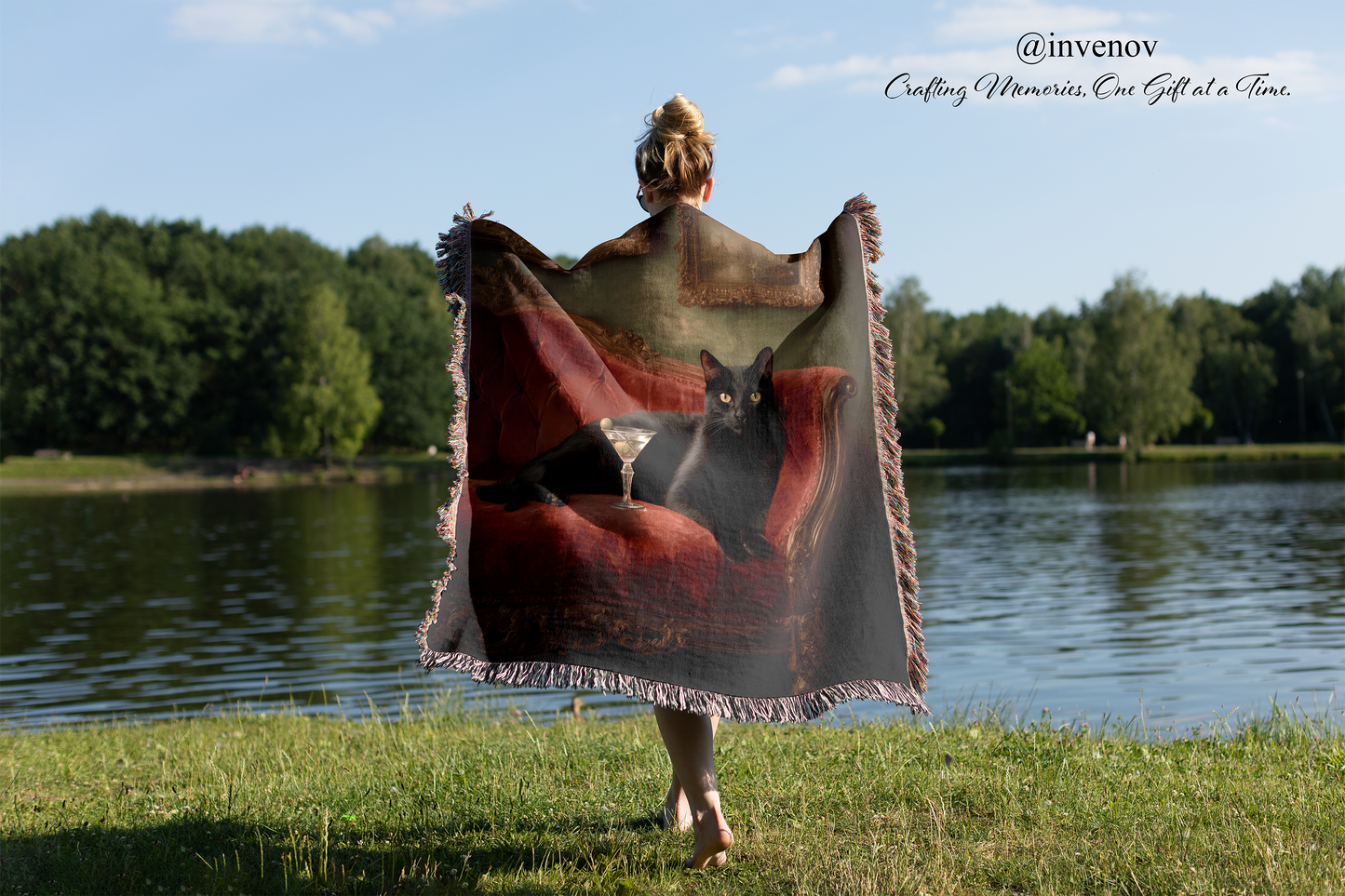 Person holding a blanket with a cat design by a lake