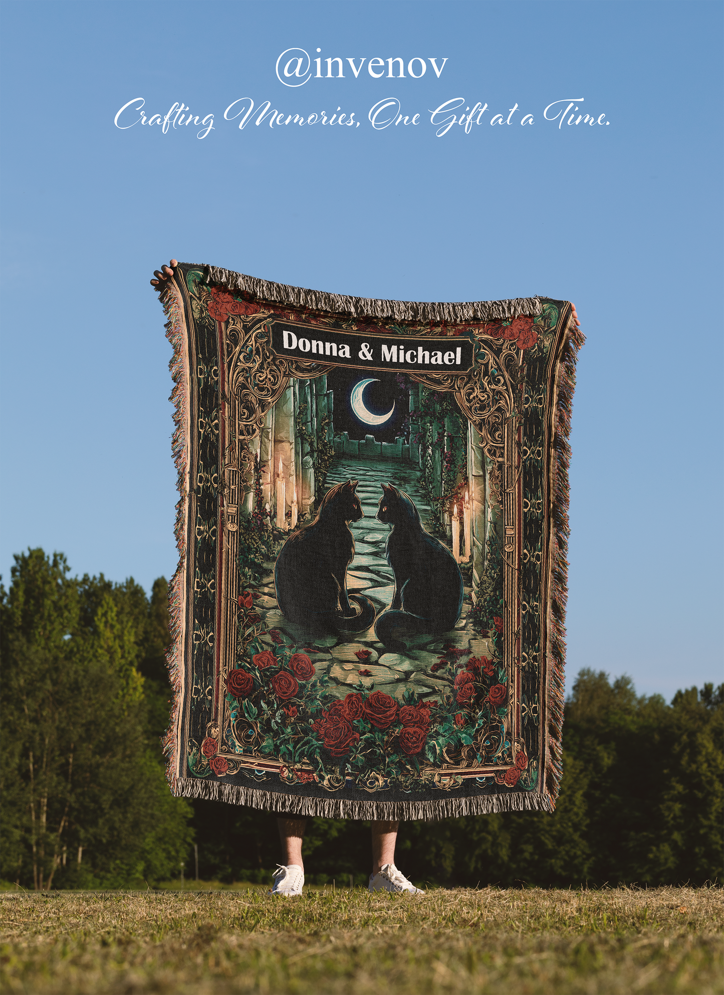 Person holding a decorative woven blanket with cats and floral patterns against a blue sky.