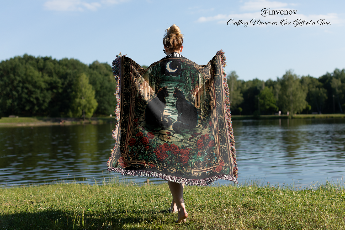 Person holding a decorative blanket with a nature design by a lake