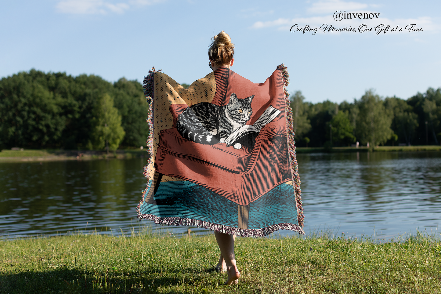 Person with a cat on a colorful blanket by a lake