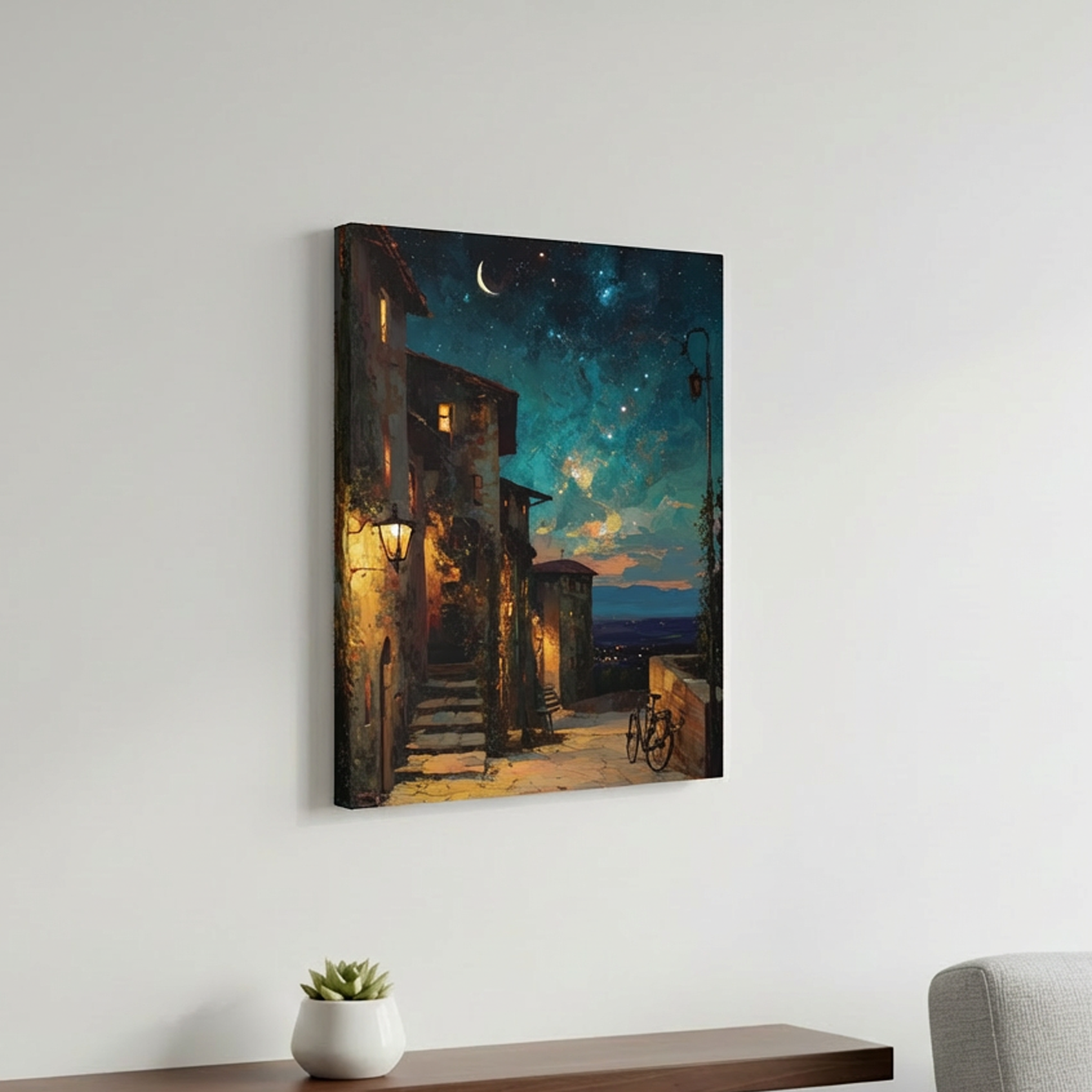 Canvas print of a night scene with a building and bicycle on a wall above a shelf with a plant and a chair.