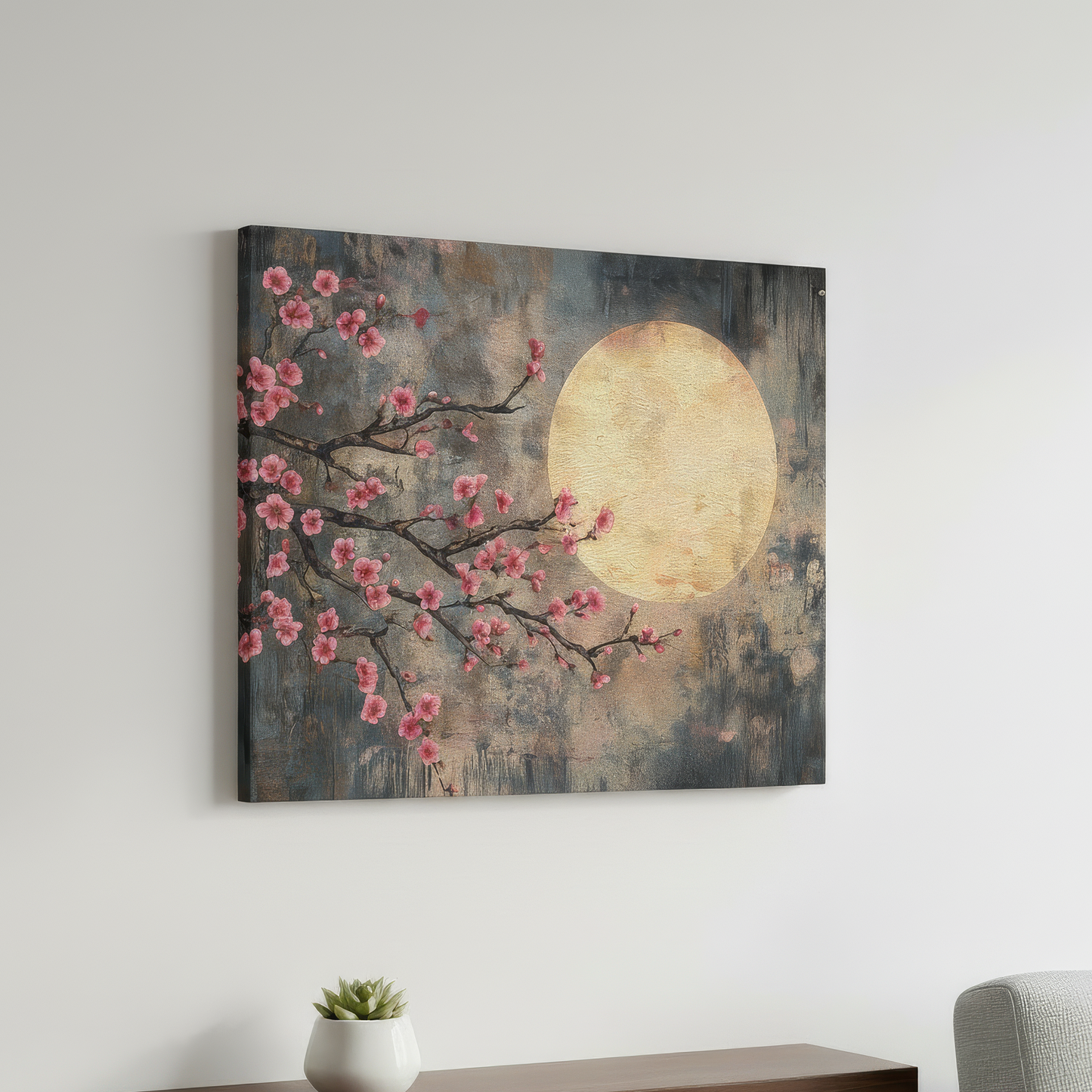 Canvas print of cherry blossoms and a moon on a wall above a desk with a plant and chair.