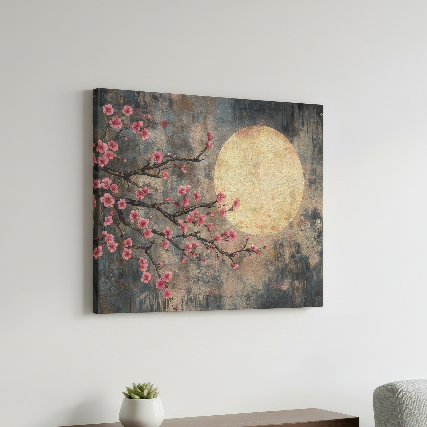 Canvas print of cherry blossoms and a moon on a wall above a desk with a plant and chair.