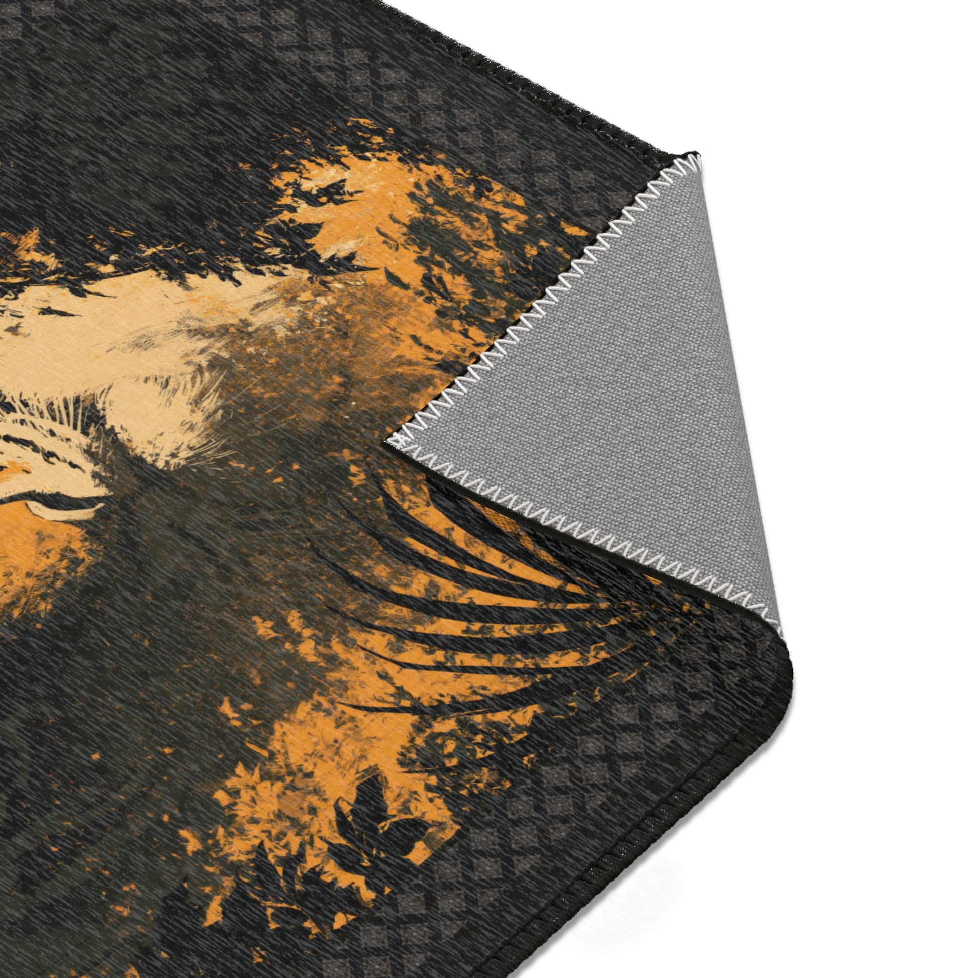 A close-up of a black and orange printed mat or pad with a folded corner revealing a gray textured backing, shown on a white background.