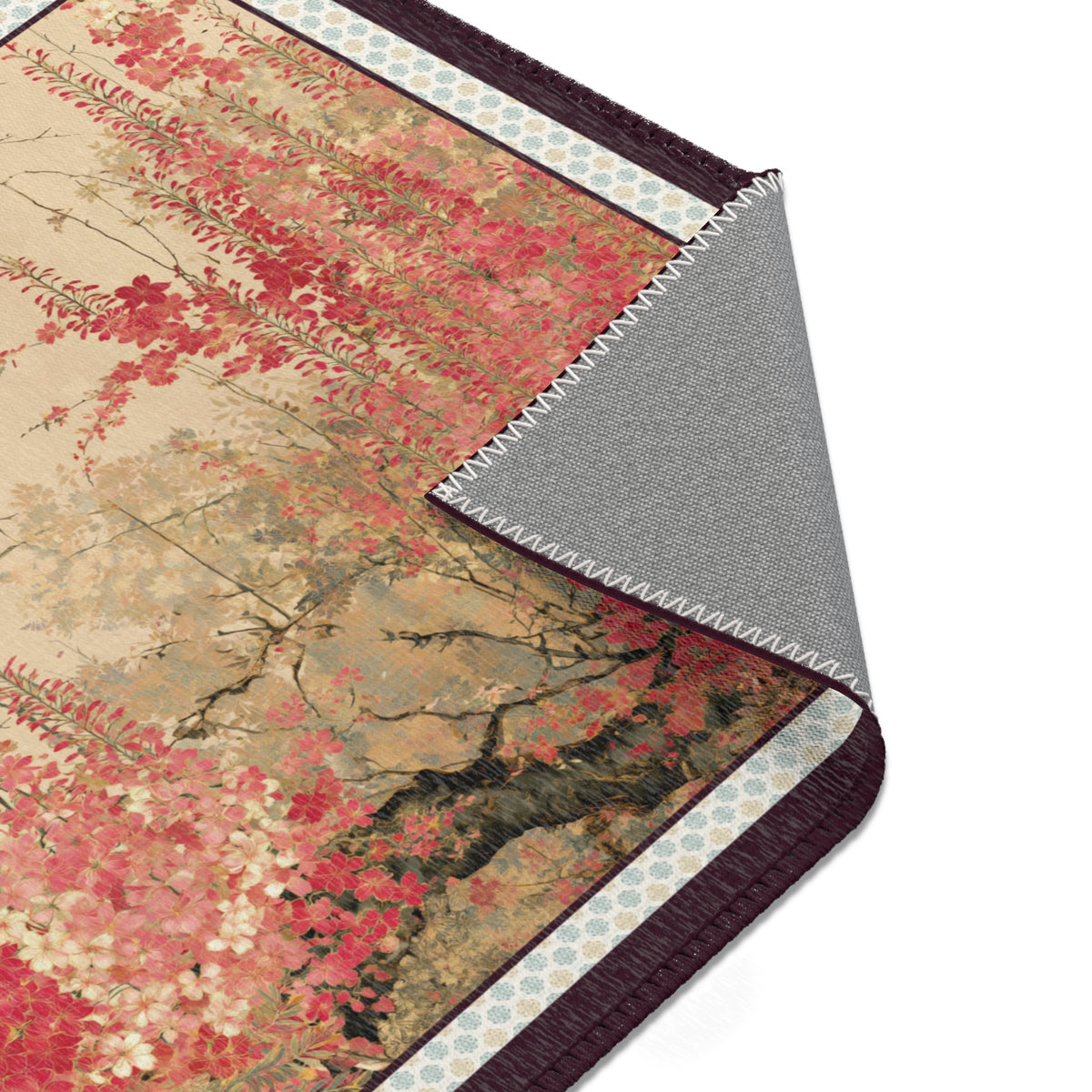 A close-up of a folded area rug showing its printed autumn floral pattern on one side and a textured gray non-slip backing on the other, set against a plain white background.