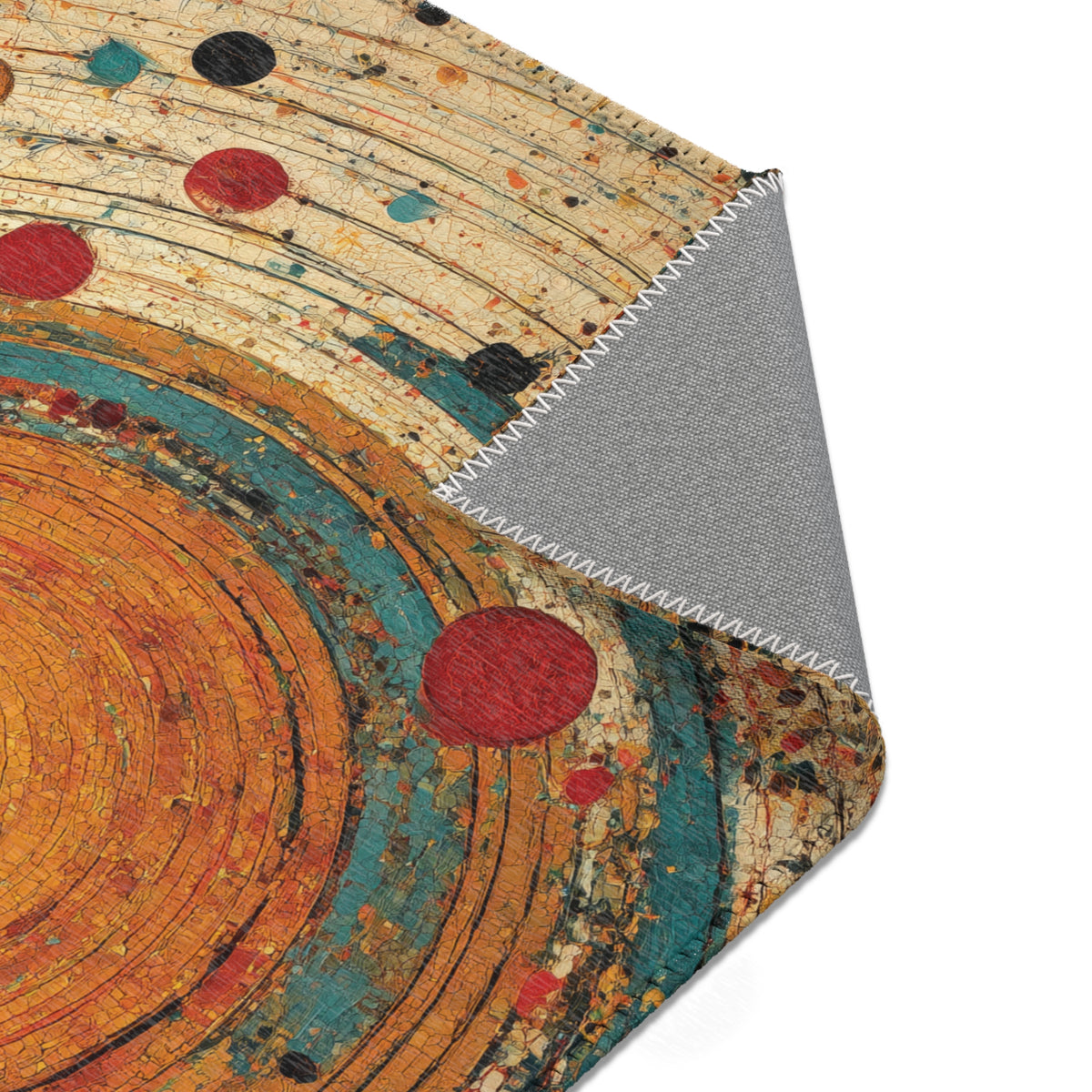 A close-up of a textured area rug with a multicolor abstract design featuring concentric circles in orange, teal, red, and black on a beige background, with one corner folded over to show a gray backing.
