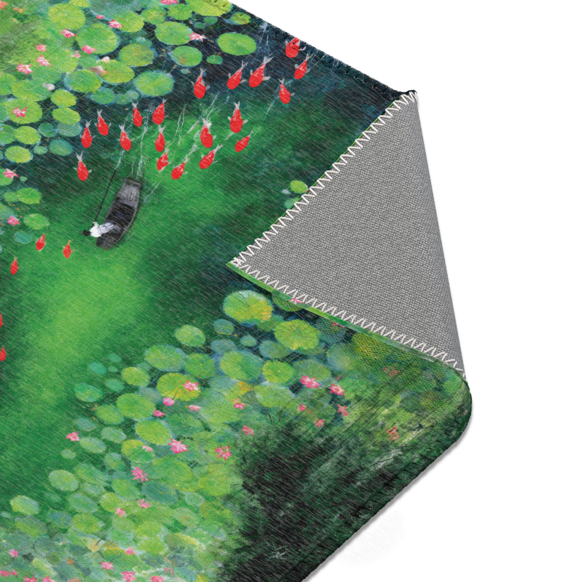 A close-up of a mat featuring a watercolor-style lotus pond design with green lily pads, red koi fish, and a small boat, shown with the corner folded over to reveal a gray textured underside.