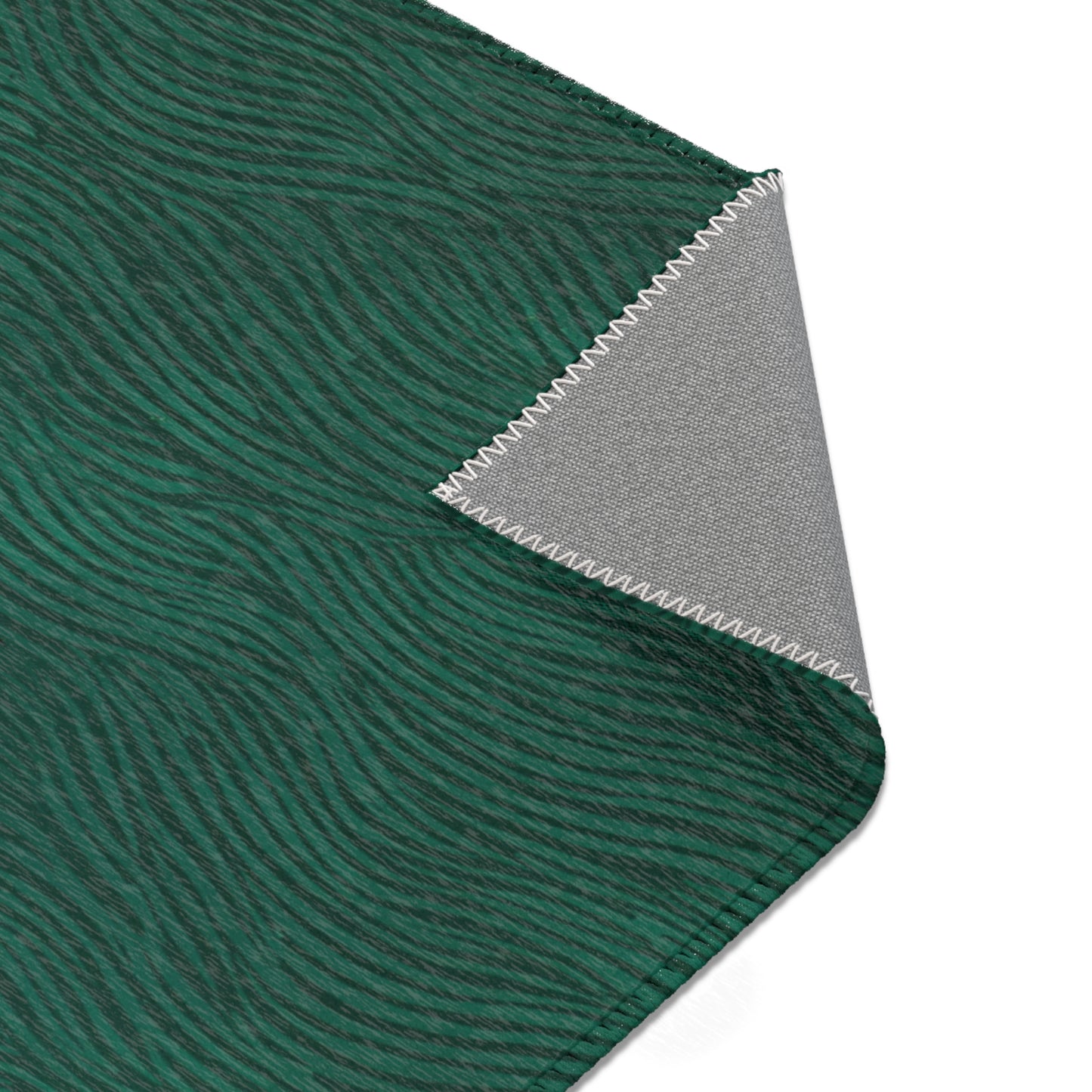 Close-up of green rug with wavy pattern and gray fabric with zigzag edge on a white background