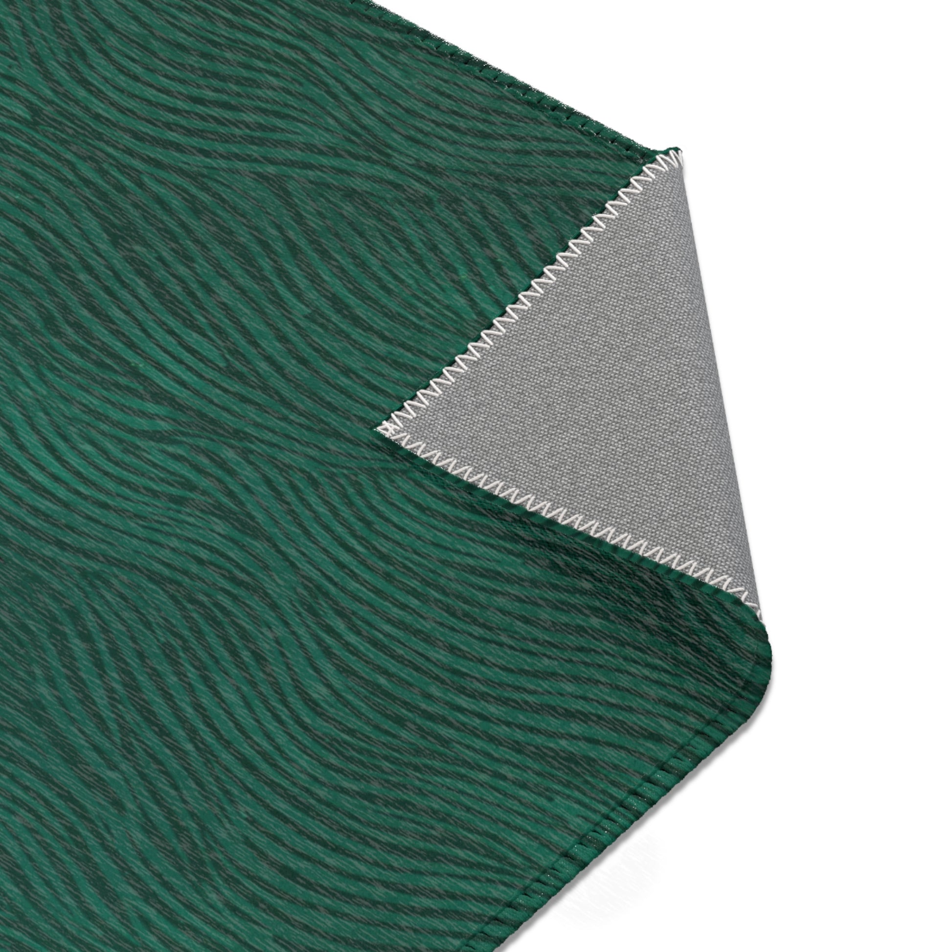 Close-up of green rug with wavy pattern and gray fabric with zigzag edge on a white background