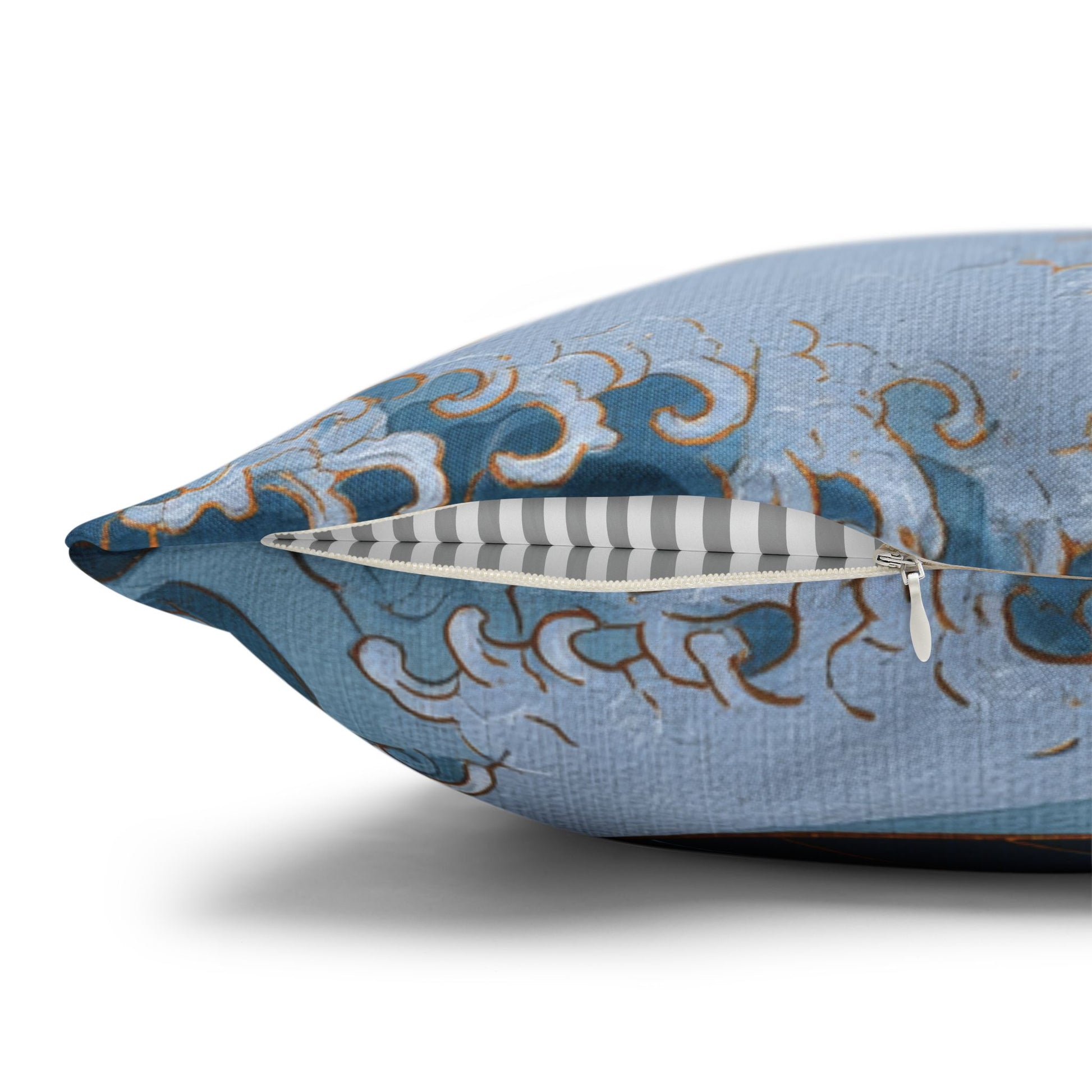 A close-up of a decorative throw pillow with a light blue fabric cover featuring a blue, white, and gold wave pattern, shown with its zipper open to reveal a striped interior.