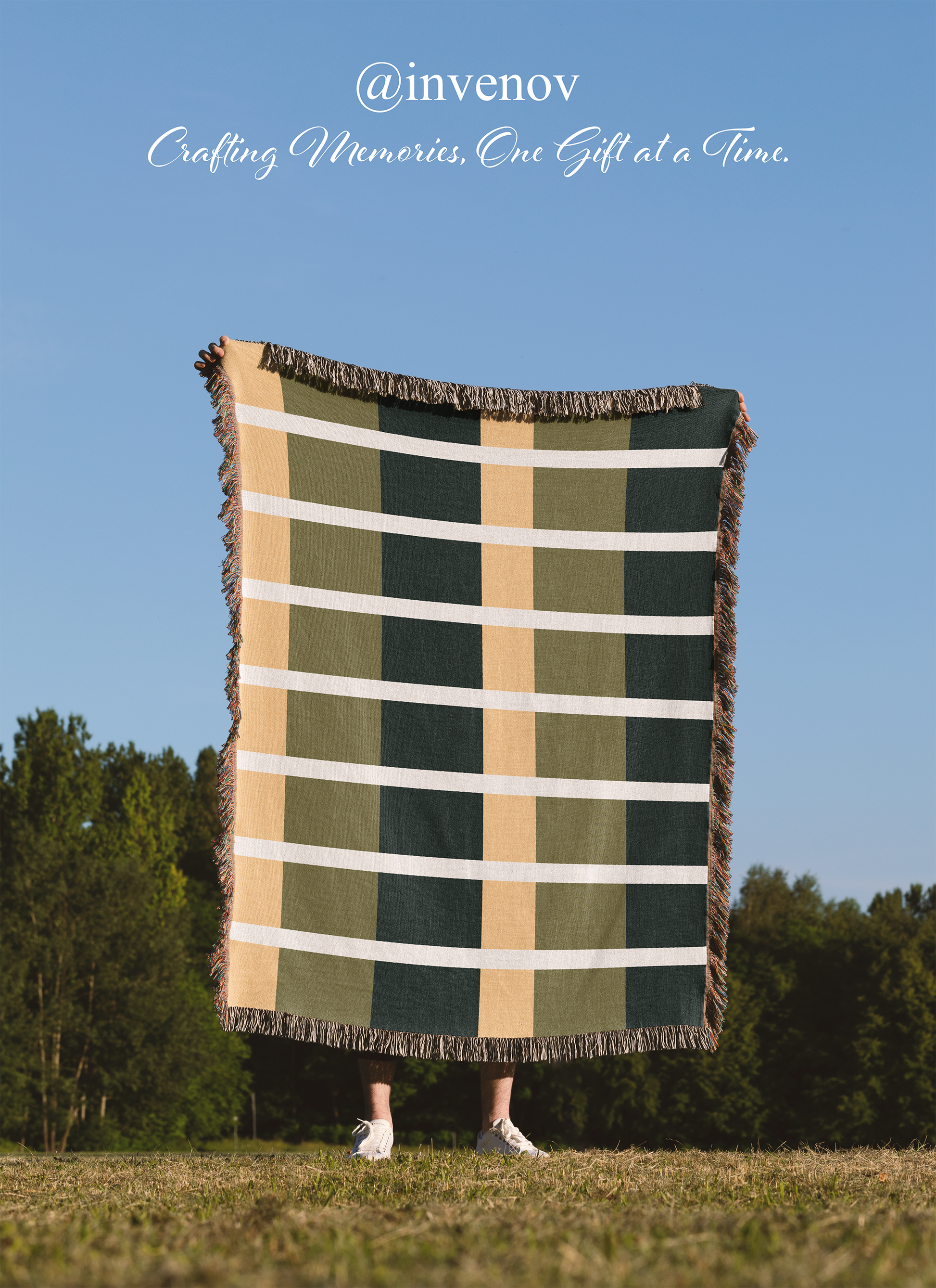 Person holding a plaid blanket outdoors with a clear blue sky and trees in the background.