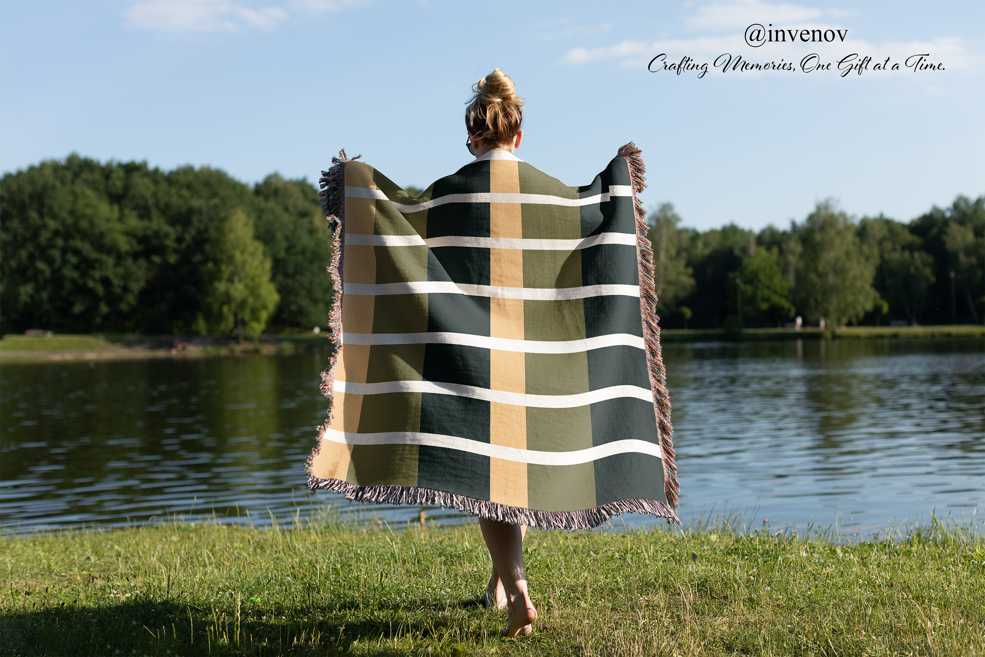 Person holding a striped blanket by a lake with trees in the background