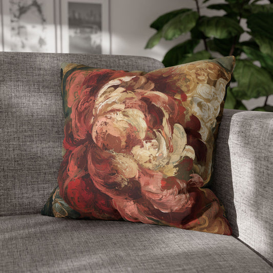 A square throw pillow featuring an abstract, painterly floral design in red, cream, and brown tones, resting on a gray textured sofa with a green plant in the background.