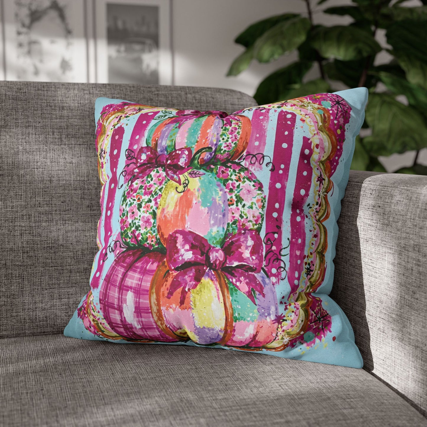 A square decorative throw pillow with a colorful autumn pumpkin design, resting on a gray fabric sofa with a blurred indoor background.