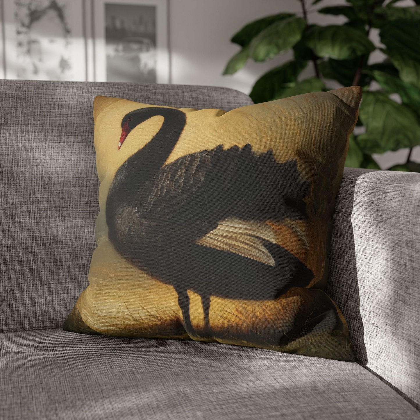 Decorative pillow with a black swan design on a gray sofa.