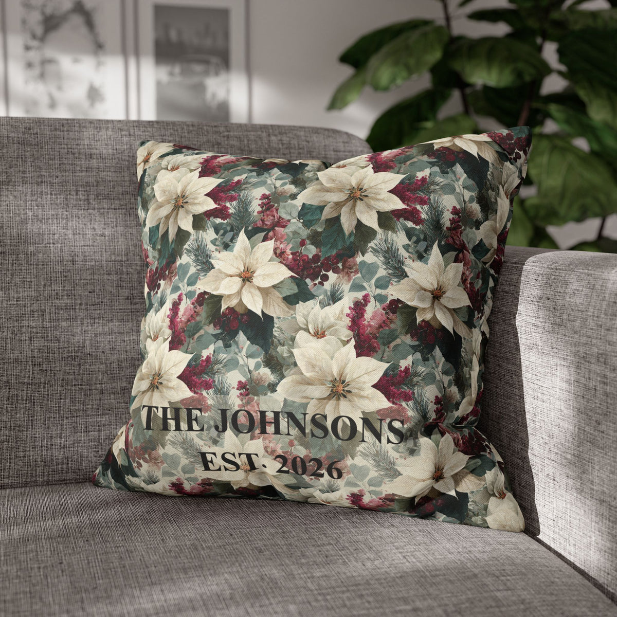 A square decorative throw pillow with a festive floral print of white poinsettias, green leaves, and burgundy berries, featuring the custom text 