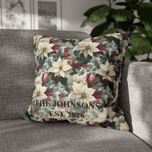 A square decorative throw pillow with a festive floral print of white poinsettias, green leaves, and burgundy berries, featuring the custom text 