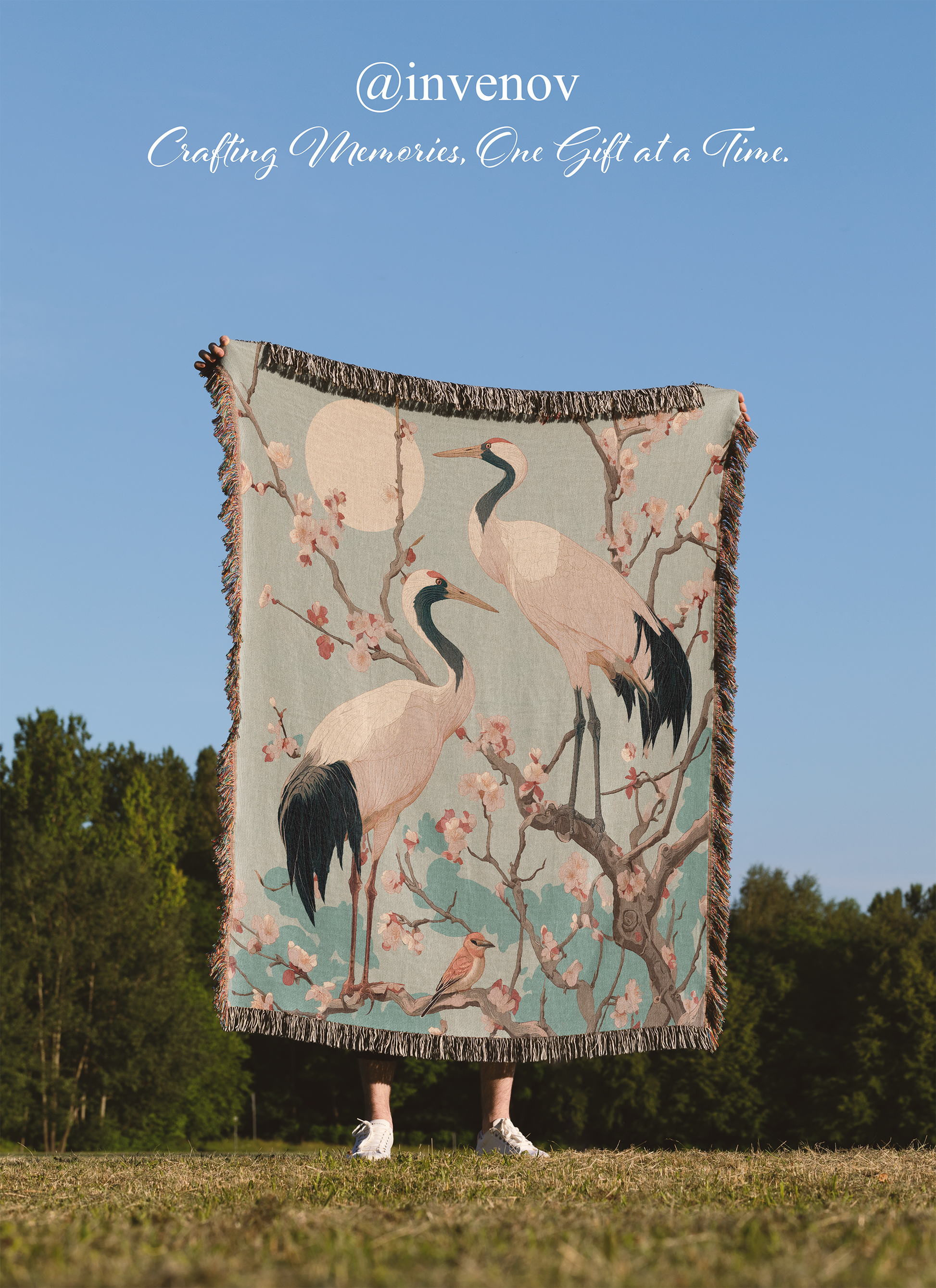Person holding a decorative blanket with crane design outdoors
