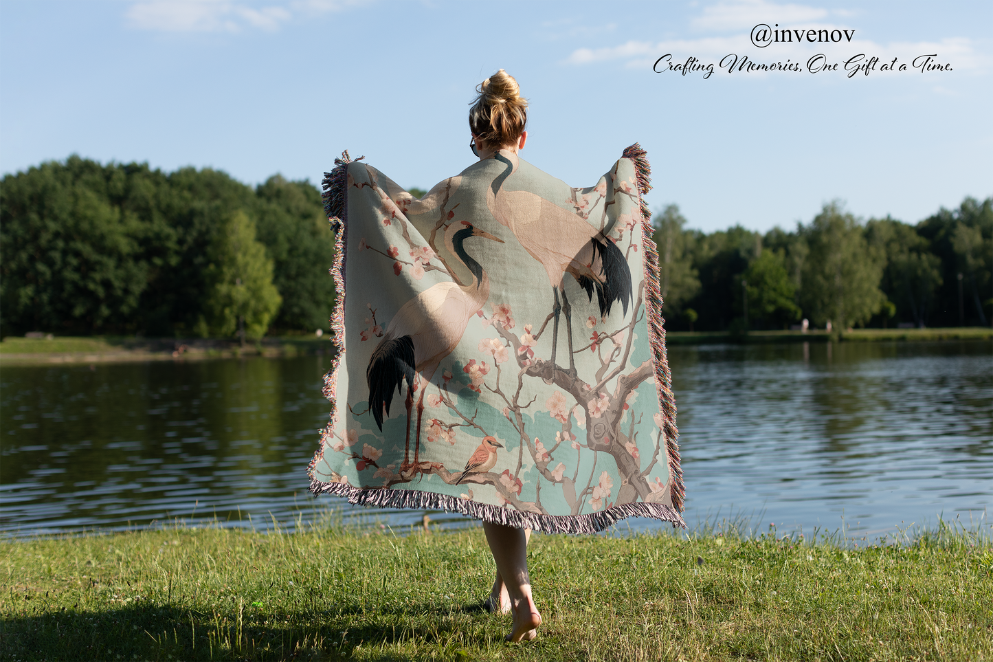 Person holding a decorative blanket with nature design by a lake