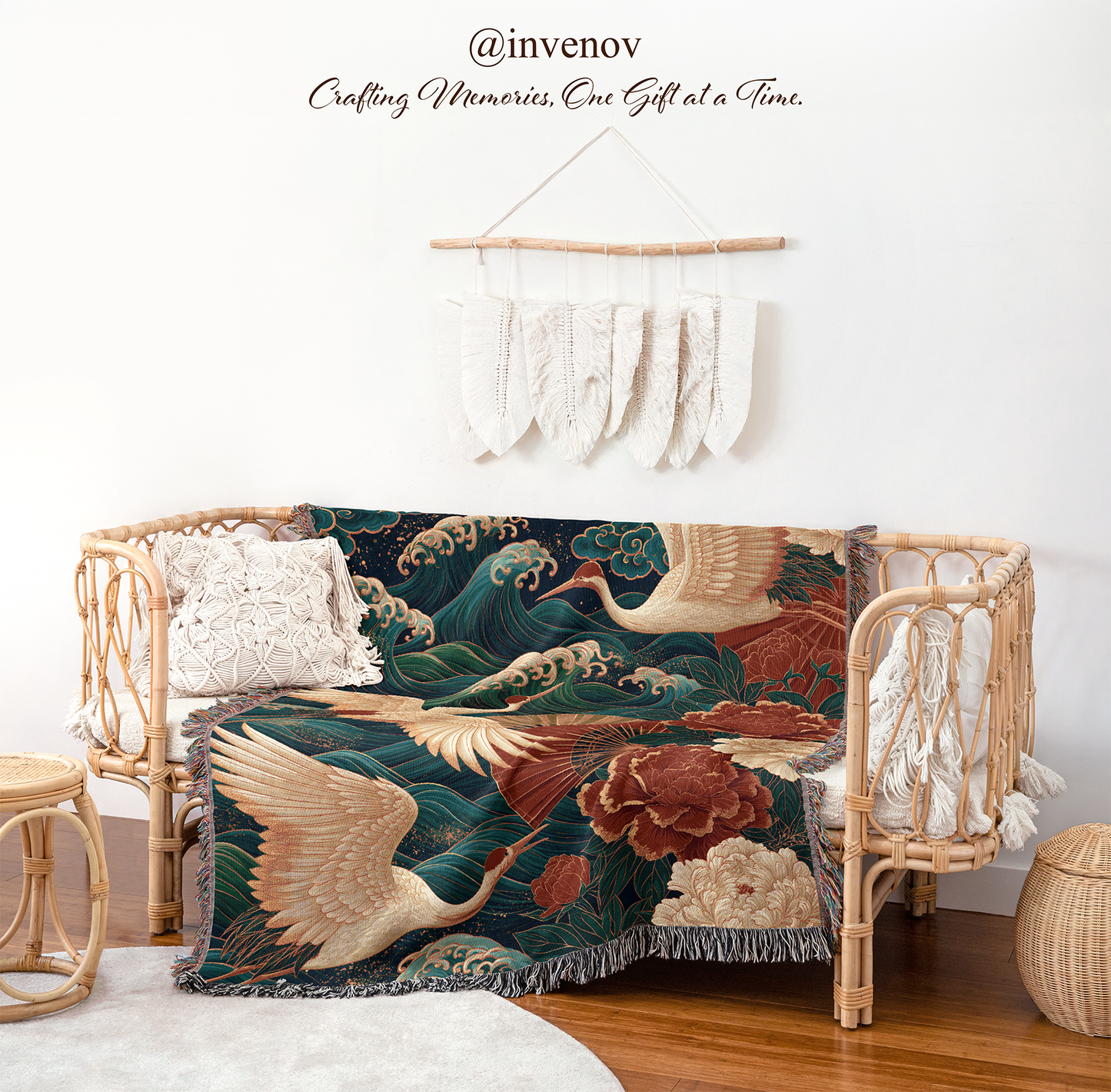 A woven throw blanket featuring a traditional Japanese wave and crane pattern in deep teal, cream, and rust tones, draped over a rattan daybed in a styled room setting.