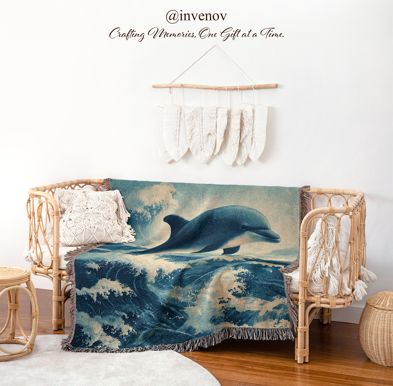 A woven throw blanket featuring a blue and white ocean wave scene with a dolphin, draped over a rattan daybed in a styled nursery or playroom setting. The room includes a white wall, macrame wall hanging, wooden floor, and other decorative rattan furniture.
