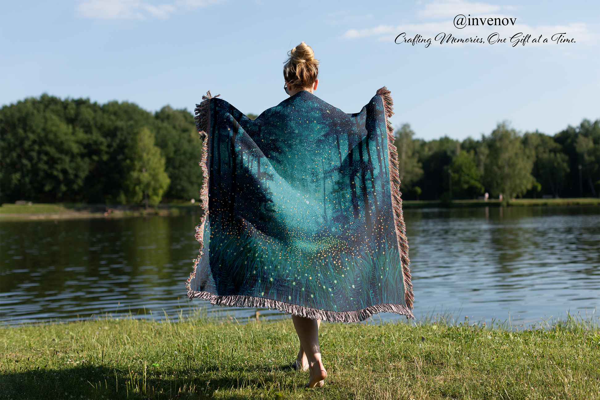 Person holding a large blue and green patterned blanket by a lake