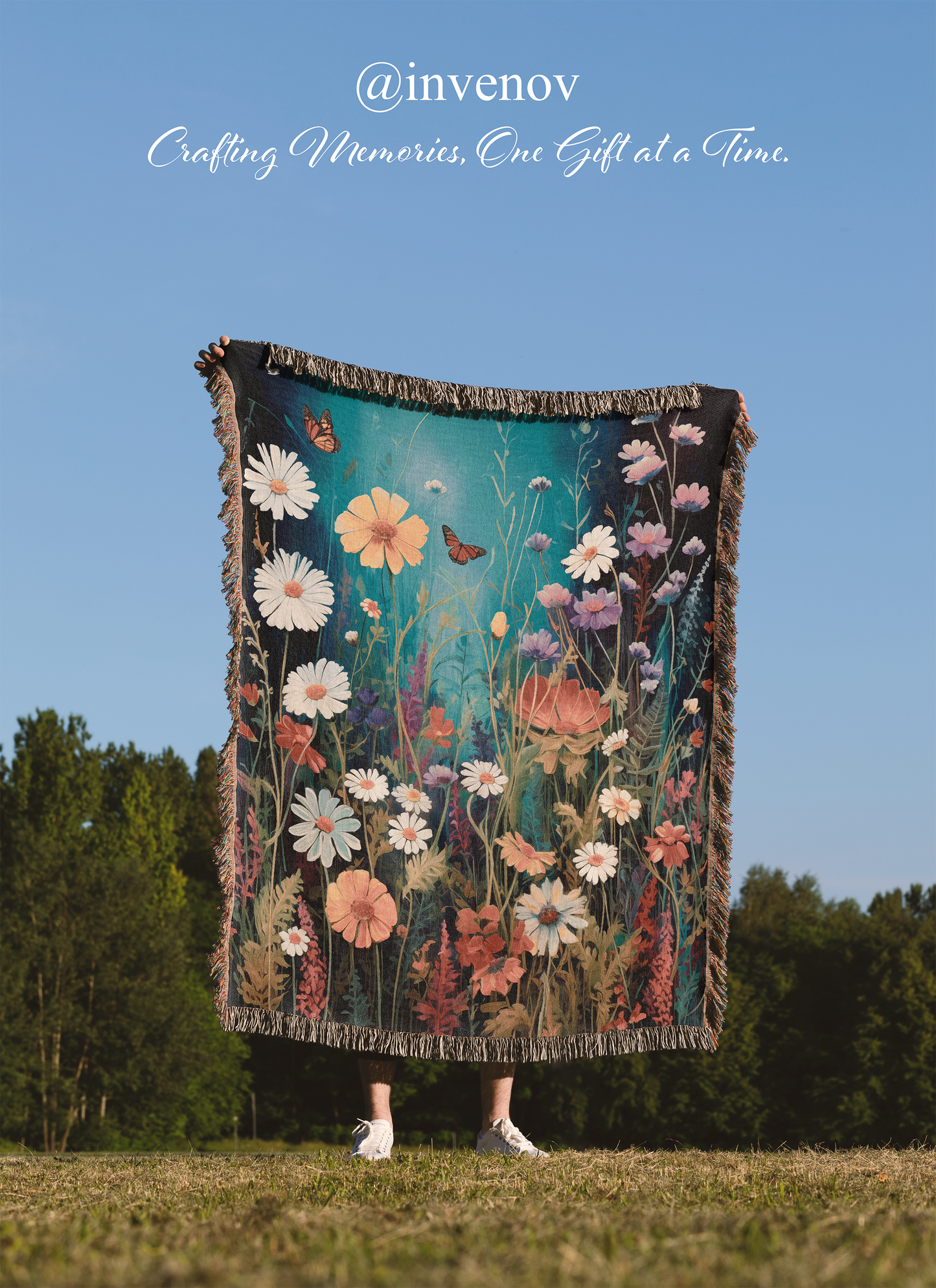 Floral patterned blanket being held up against a blue sky with trees in the background