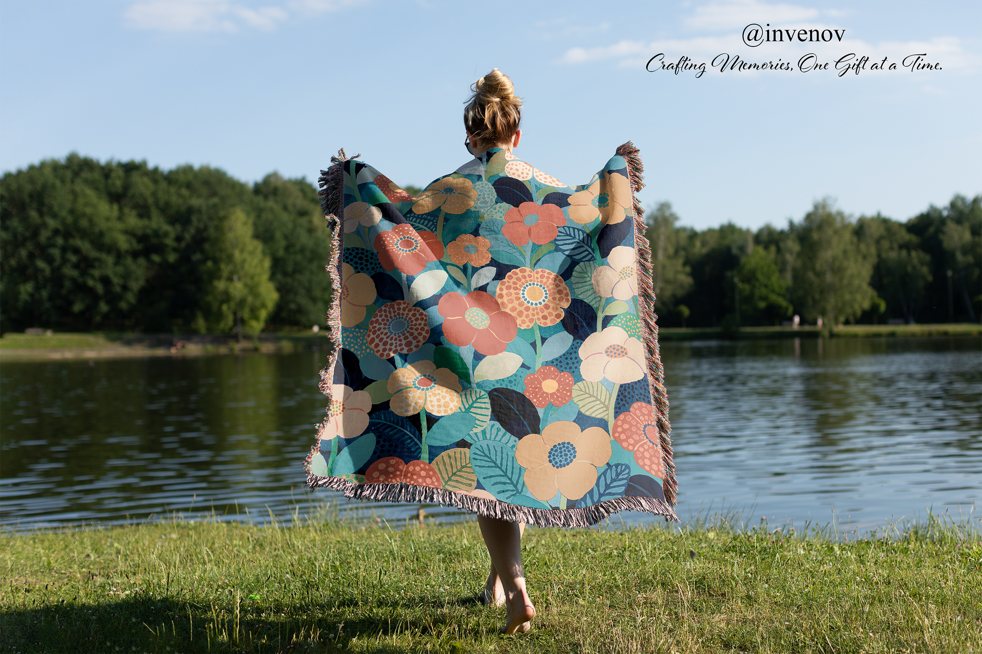 Person holding a colorful floral-patterned blanket by a lake