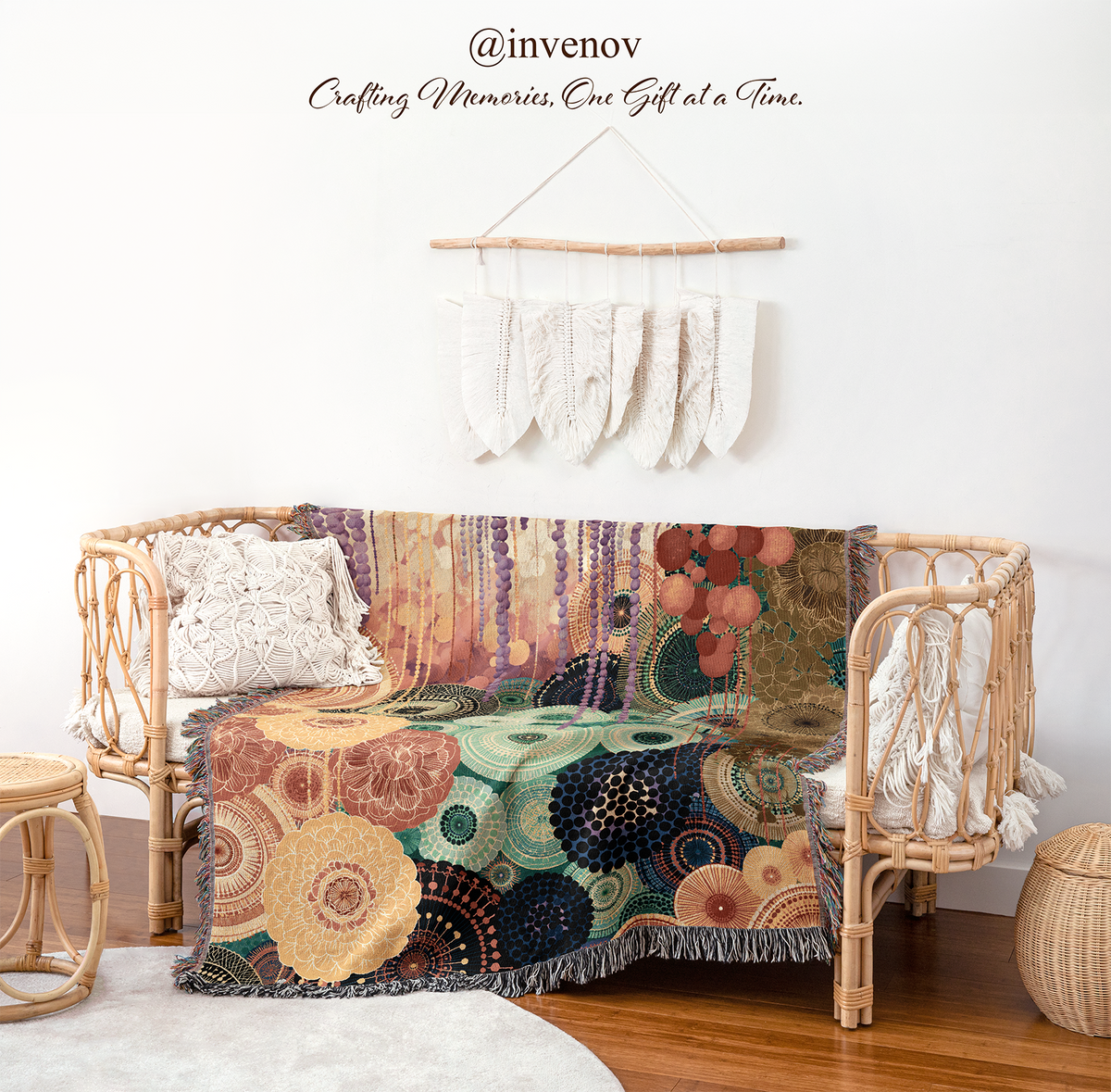 A woven rattan daybed styled with a colorful abstract patchwork throw blanket, white textured pillows, and a matching white fringed throw, set in a bright room with a wooden floor and a boho wall hanging.