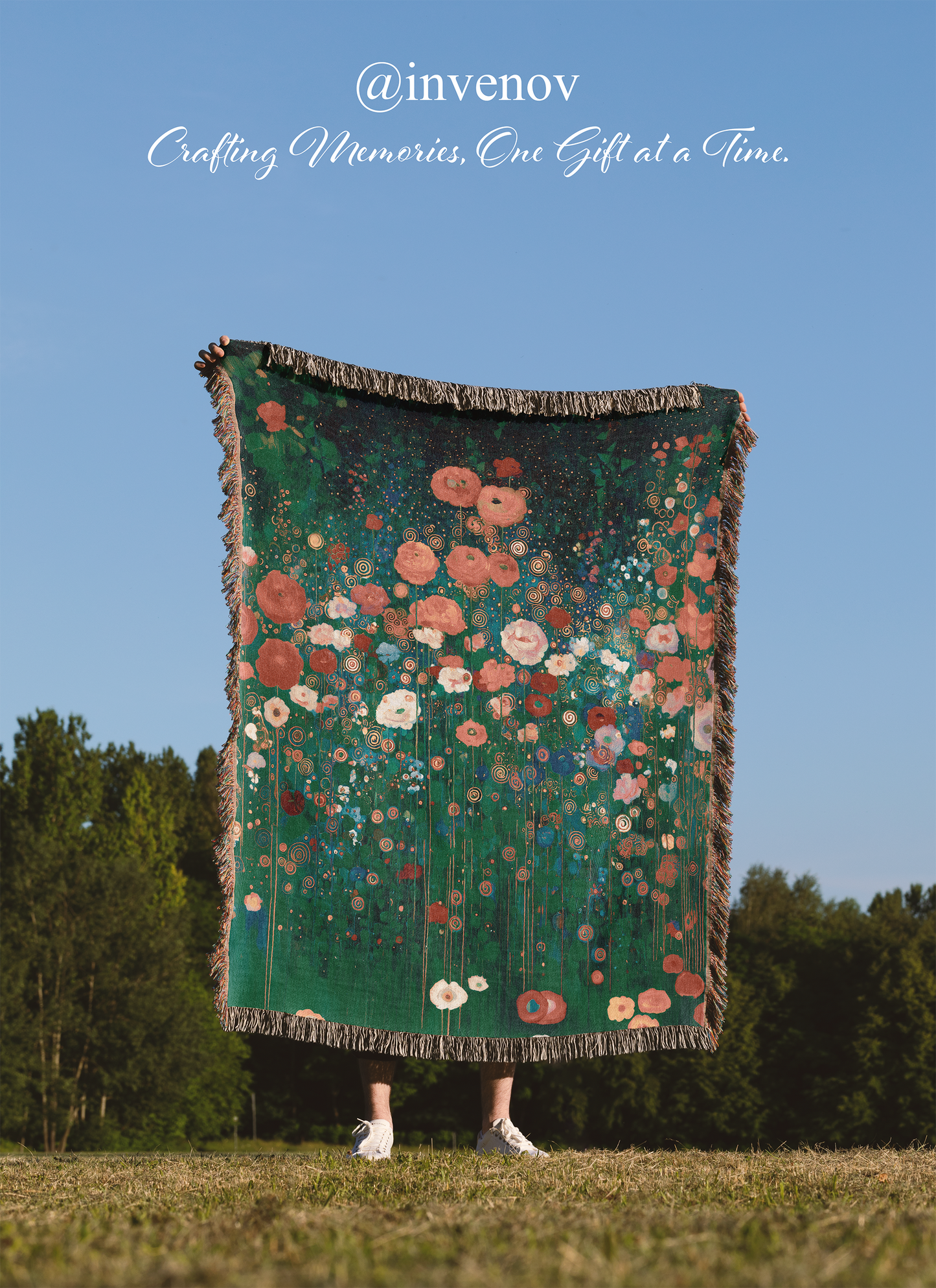 Floral patterned blanket being held up against a blue sky with trees in the background
