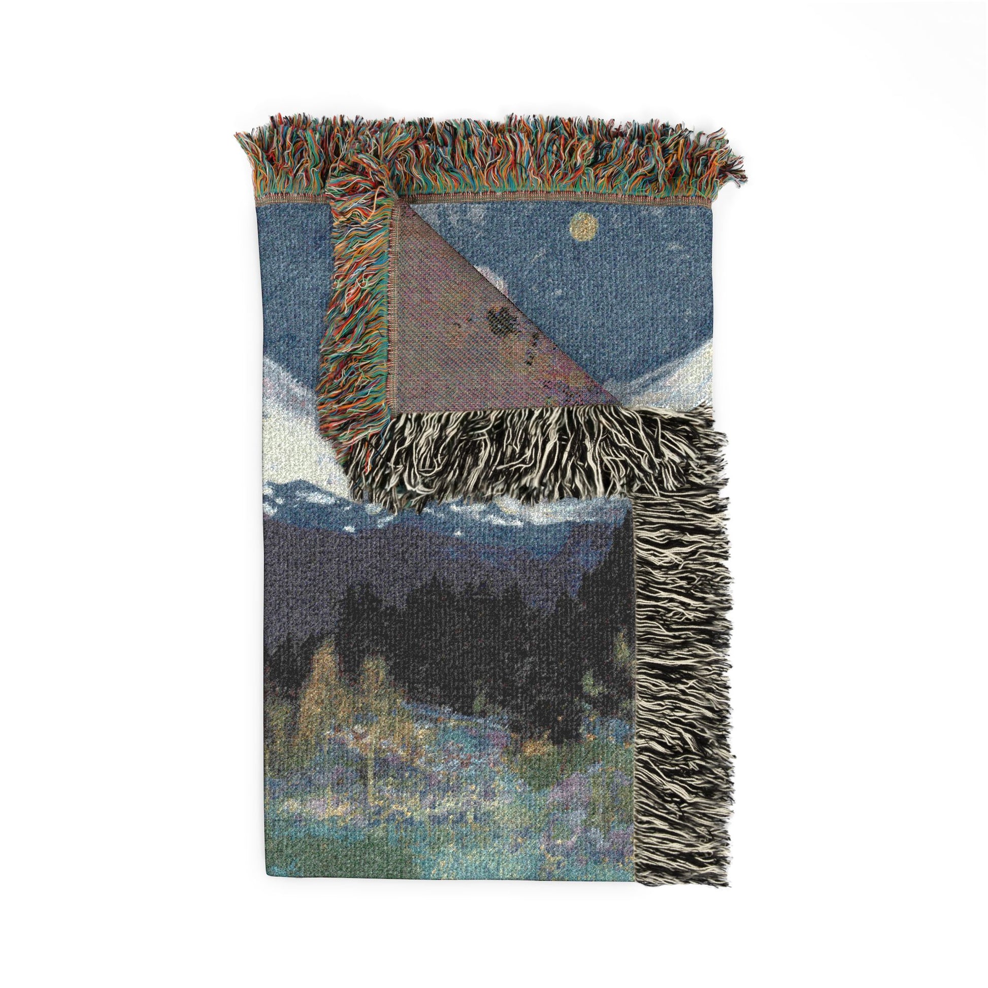 Woven blanket with landscape design featuring mountains and trees on a white background