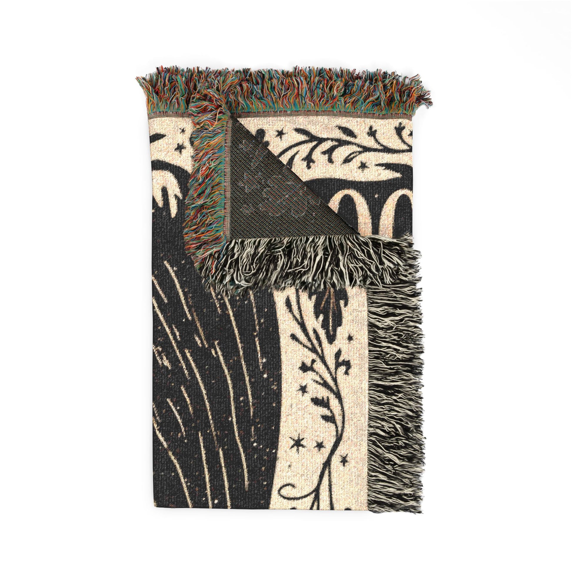 A rectangular woven throw blanket with fringe, featuring a black and cream botanical pattern with stars and abstract leaf designs, shown on a plain white background.