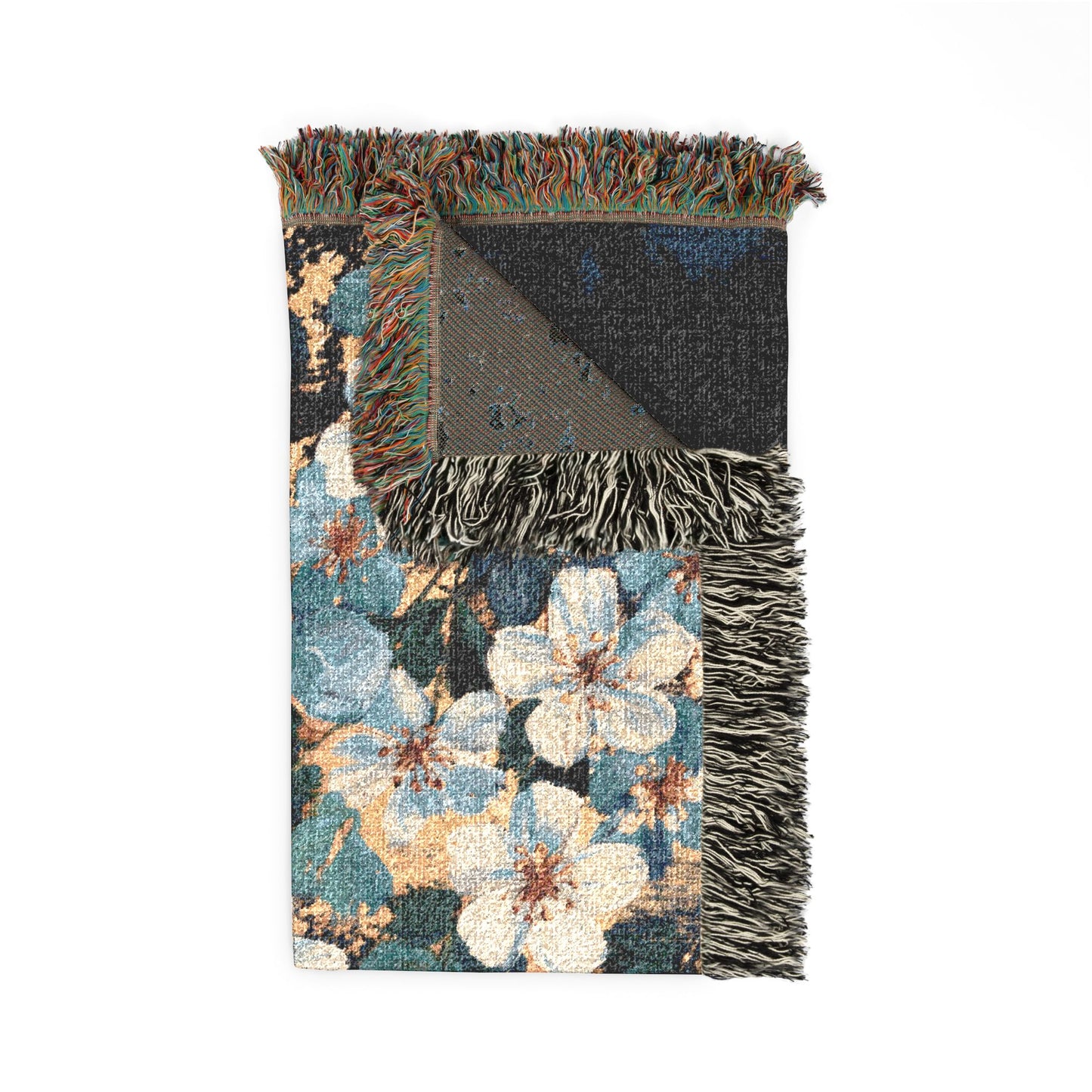 A folded woven throw blanket with a floral pattern, featuring cream and blue flowers, teal and brown leaves, and dark gray/black fringed edges, shown on a plain white background.