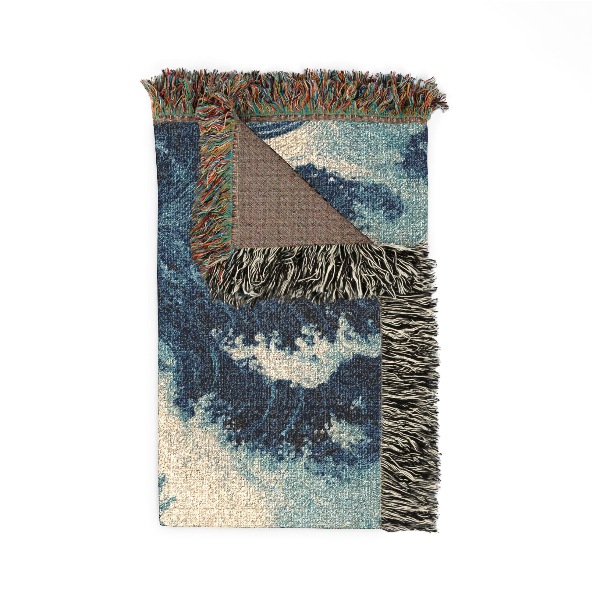 A rectangular woven throw blanket with a blue and beige ocean wave pattern, featuring multicolor fringe on the top and sides and a brown reverse side, shown on a plain white background.