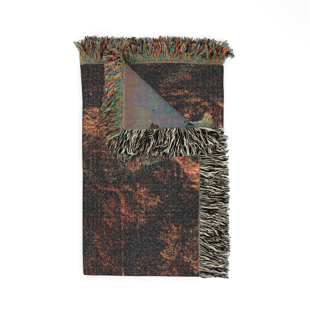 A folded woven throw blanket with fringed edges, featuring a distressed abstract pattern in dark charcoal gray, rust orange, and brown tones, with a small iridescent triangle detail near the top.