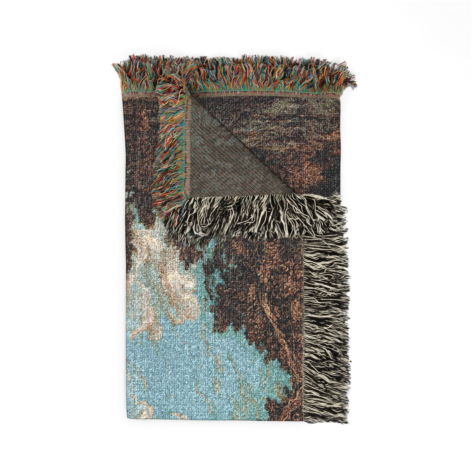 A folded woven throw blanket with fringed edges, featuring an abstract pattern in light blue, brown, beige, and dark gray on a white background.