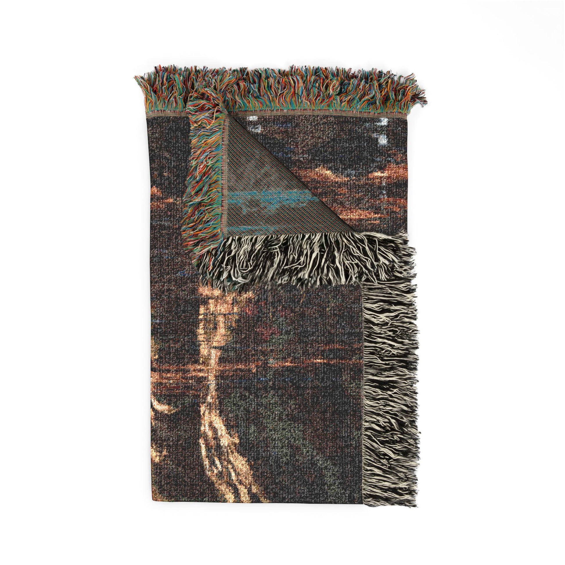 A folded woven throw blanket with fringed edges, featuring a dark charcoal and brown abstract pattern with hints of teal and cream, shown on a plain white background.
