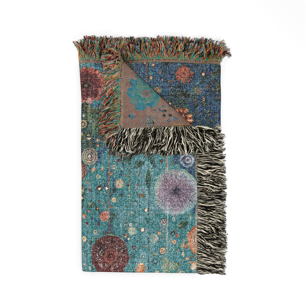A folded woven throw blanket with fringed edges, featuring a multicolor abstract pattern in teal, blue, purple, rust, and brown on a white background.