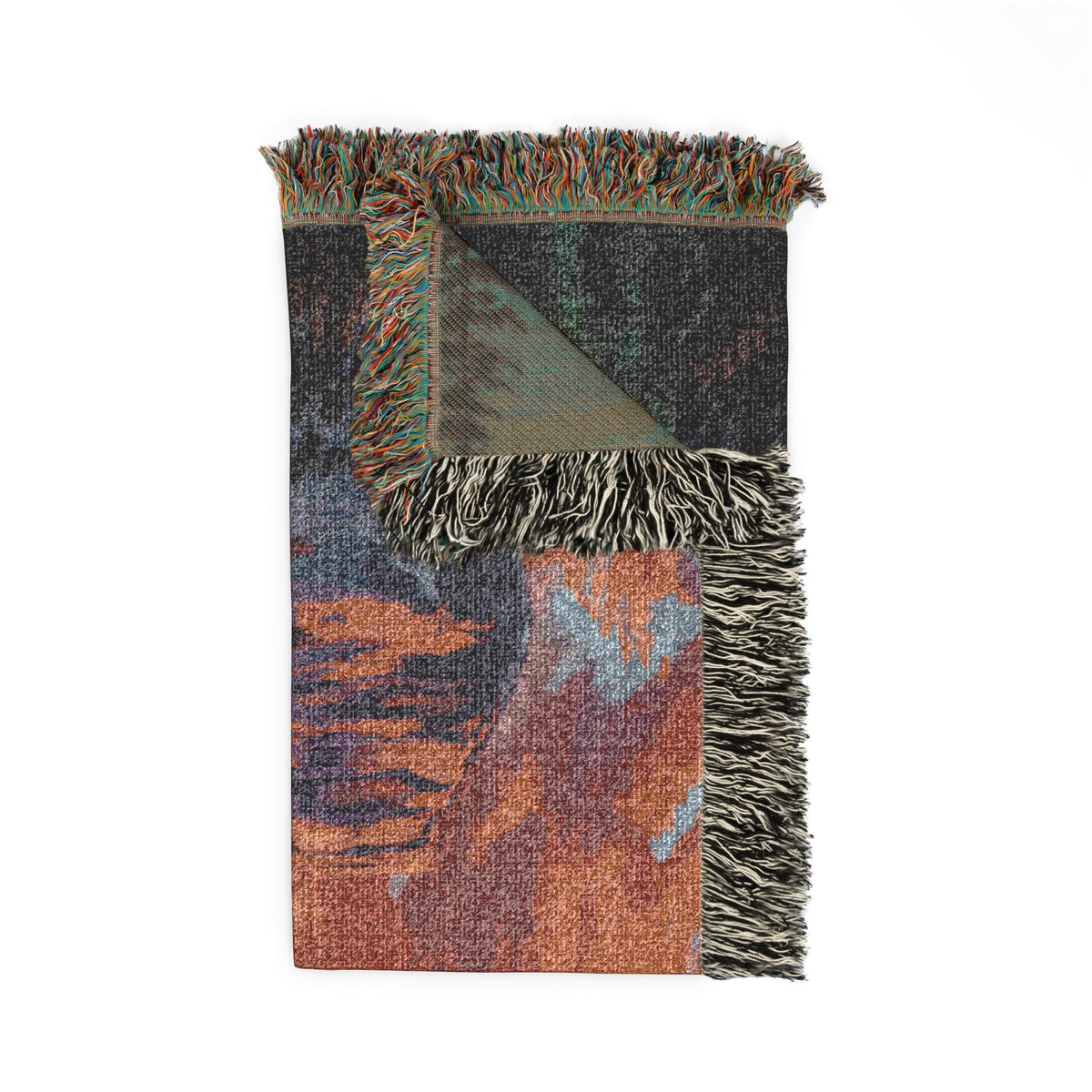 A folded woven throw blanket with multicolor abstract patterns in rust orange, slate blue, and charcoal gray, featuring black and white fringed edges on a white background.