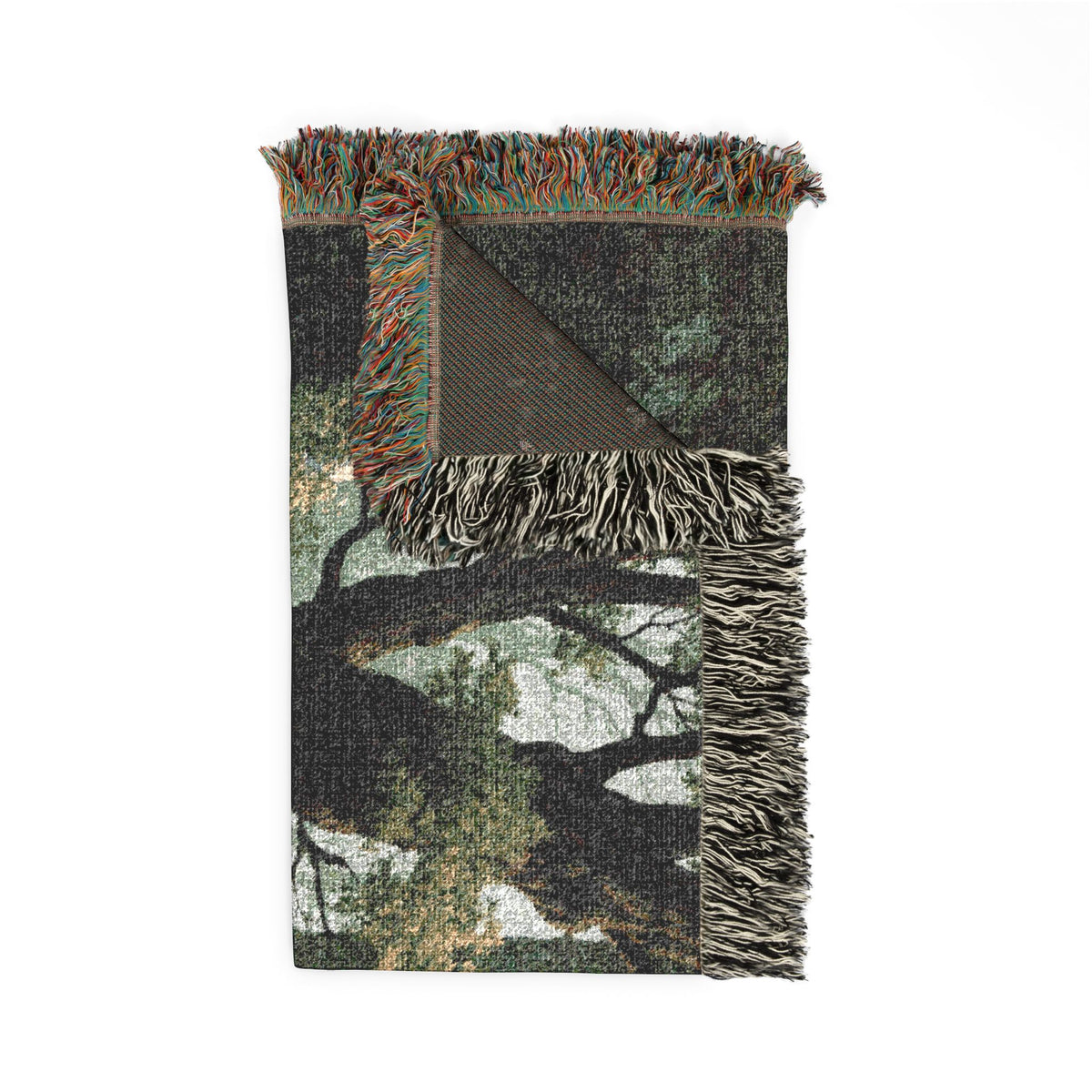 A folded woven throw blanket featuring a woodland tree branch and leaf pattern in shades of green, brown, black, and beige, with fringed edges.